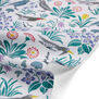 Detail of tea towel with a pattern of birds and flowers in muted colours on white background.  
